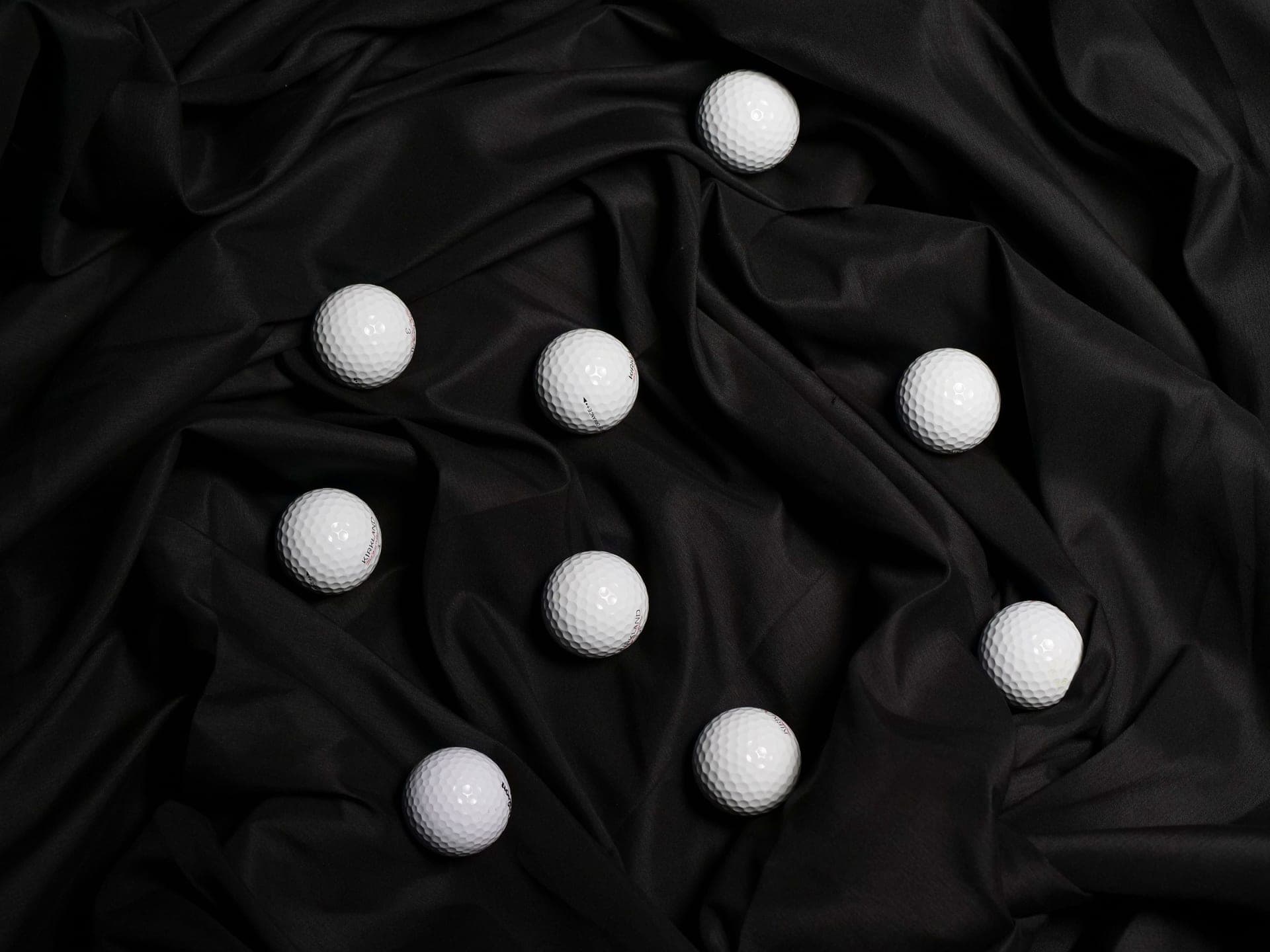 Golf balls and tees arranged on a dark surface